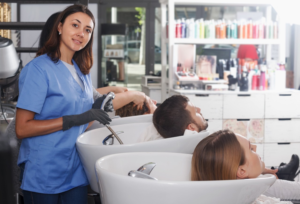 Female hairdresser washing man's hair in salon