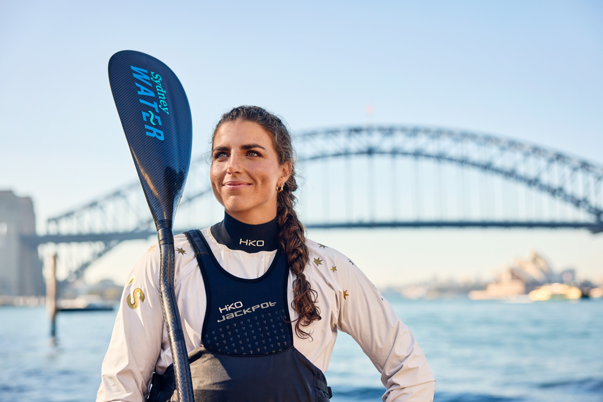 Image of Jess Fox holding paddle, with Sydney Harbour Bridge in background