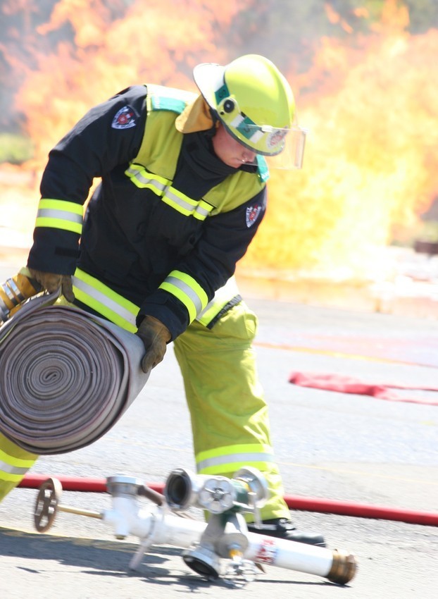 Fireman rolling out hose with fire in background