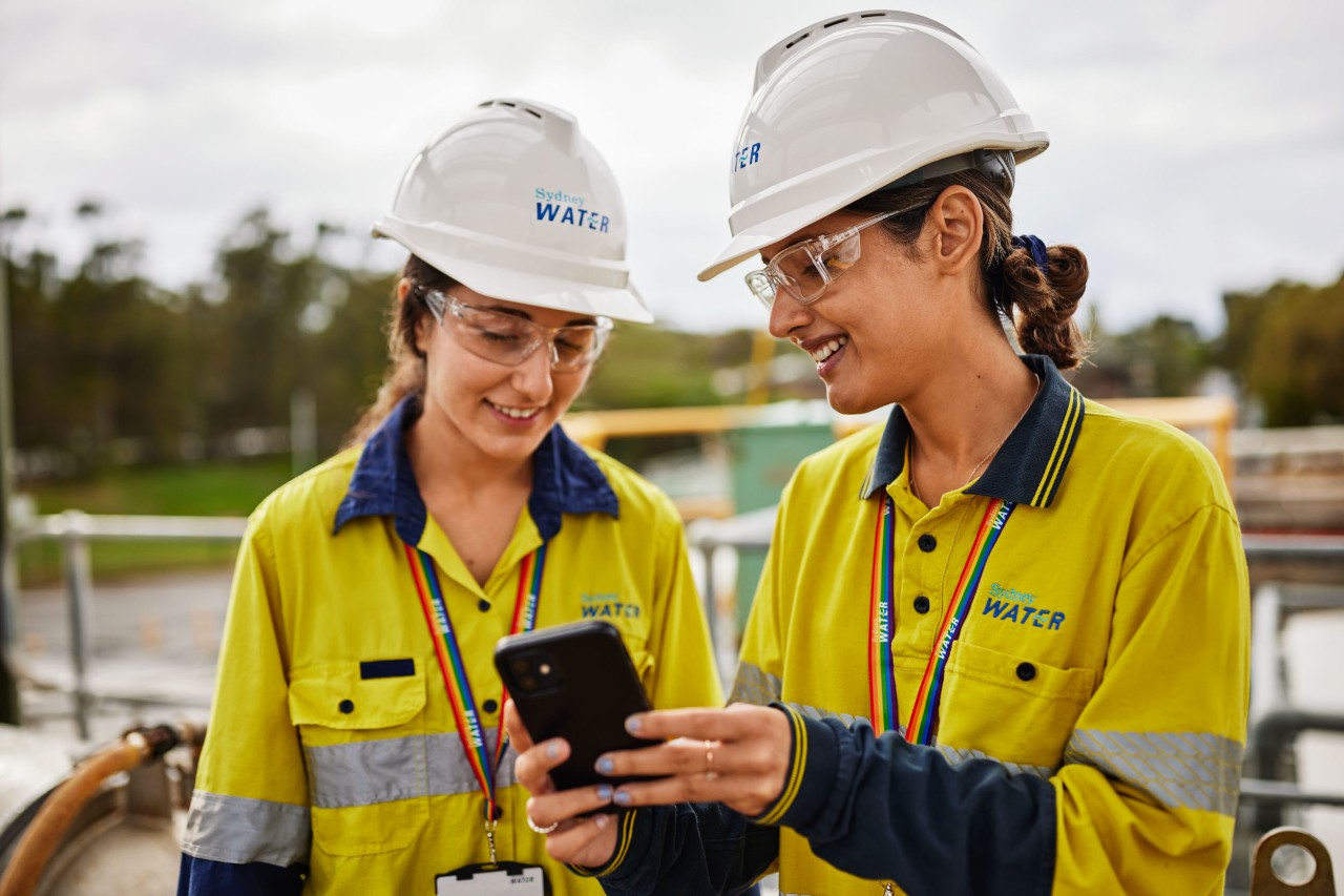 Two female operational employees at the Malabar Water Resource Recovery Facility looking at a phone. 