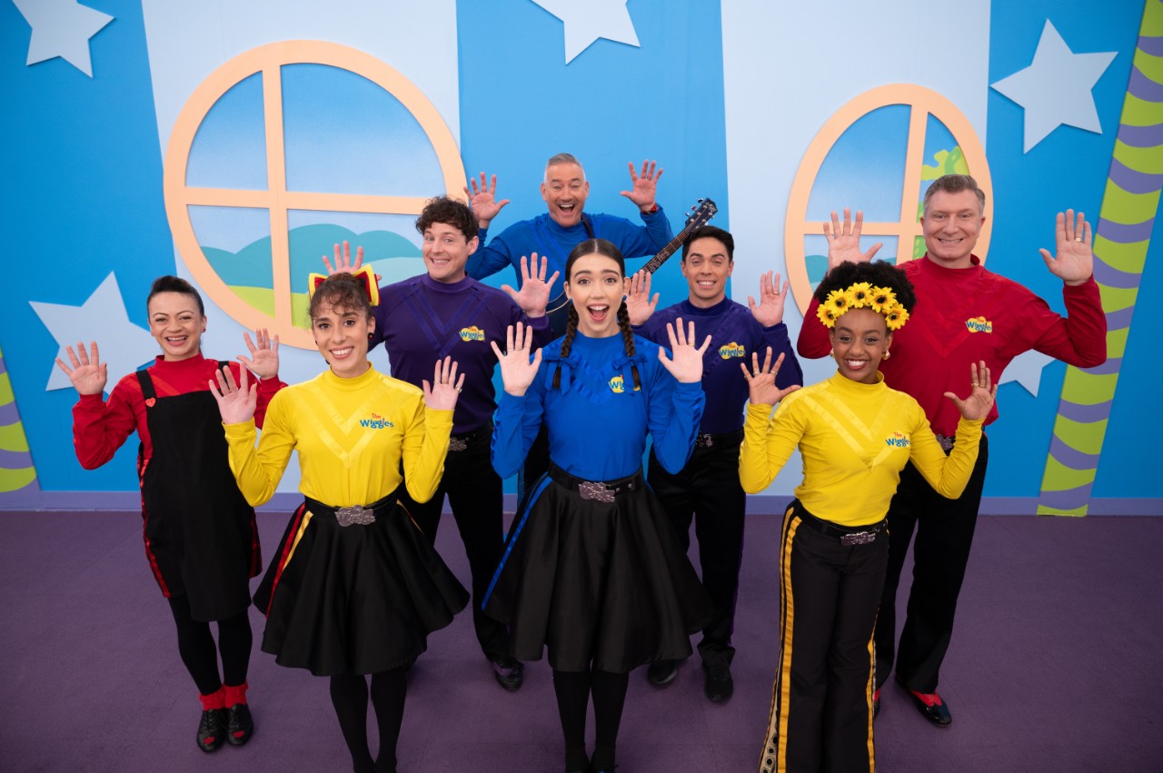 The wiggles group with their hands up