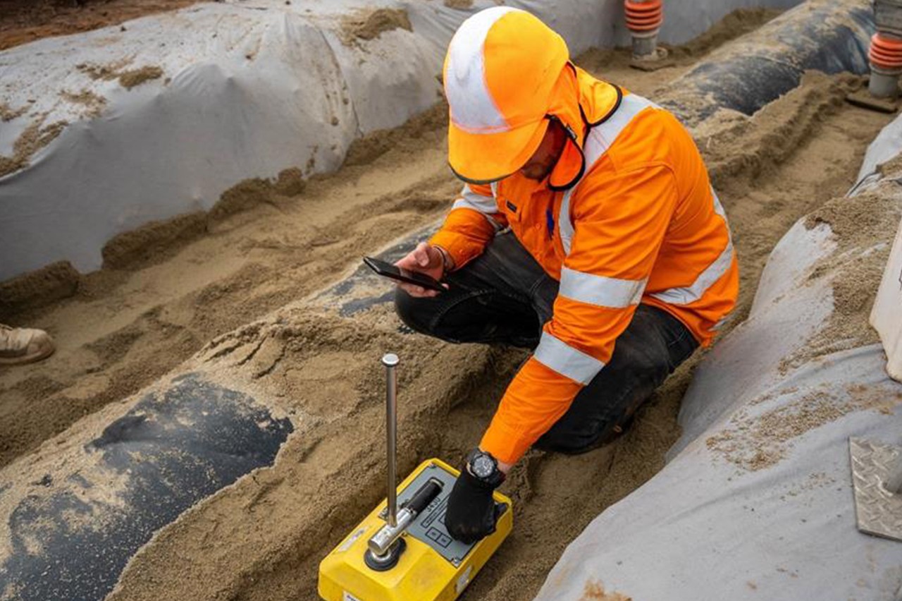 Construction field staff in orange vest working on pipe bedding