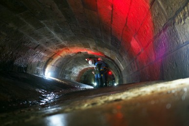 A person walking through the dimly lit Tank Stream culvert