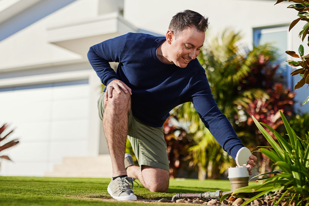 A man reading a water meter in the front garden