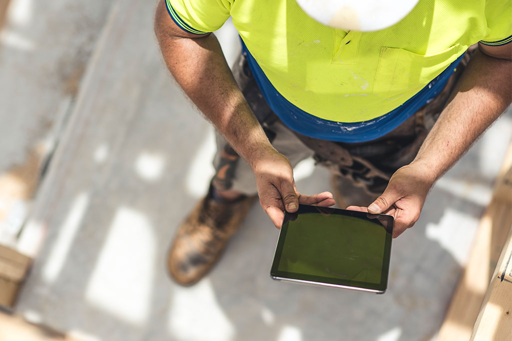 Builder on worksite holding tablet