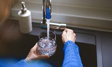 Woman filling glass of water at a kitchen sink