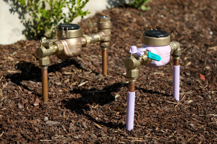 A photo of a drinking water meter and a purple recycled water meter.