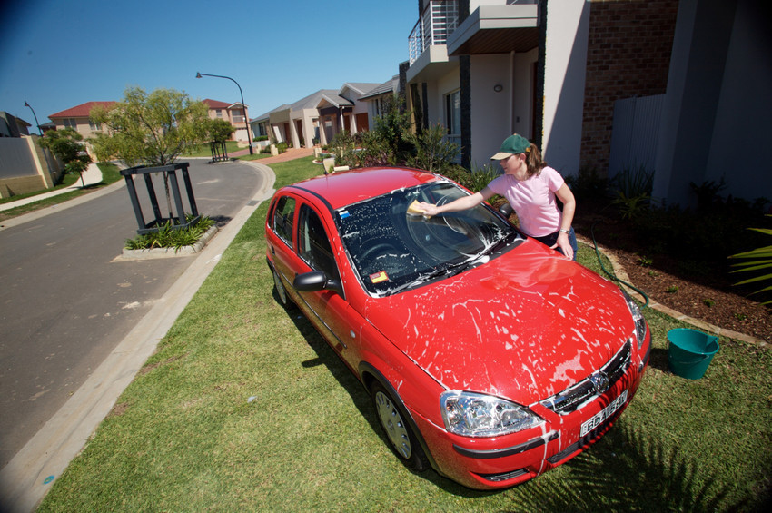 A women using a bucket and sponge to wash her car with recycled water