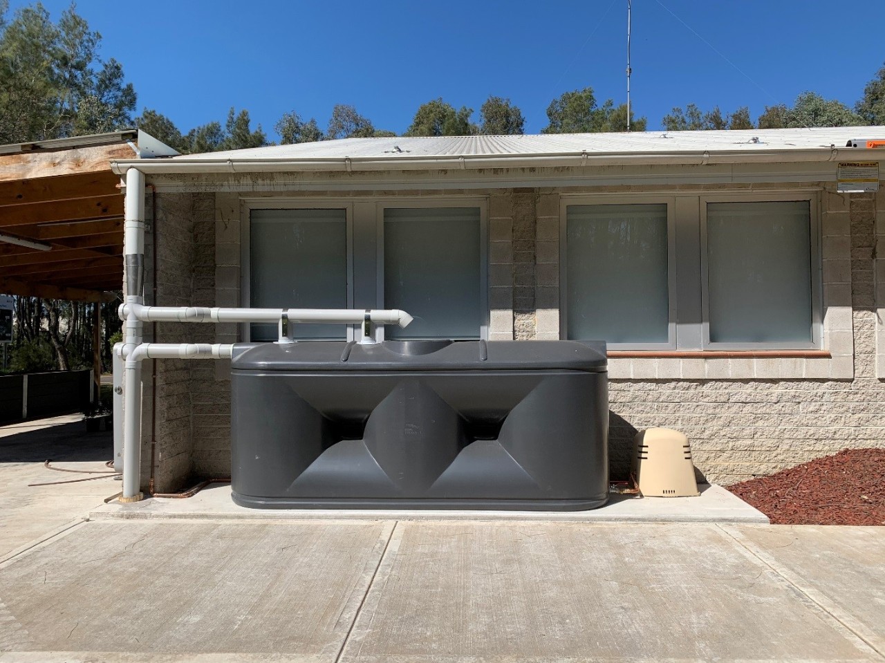 A large rainwater tank and how it fits next to a dwelling or structure 
