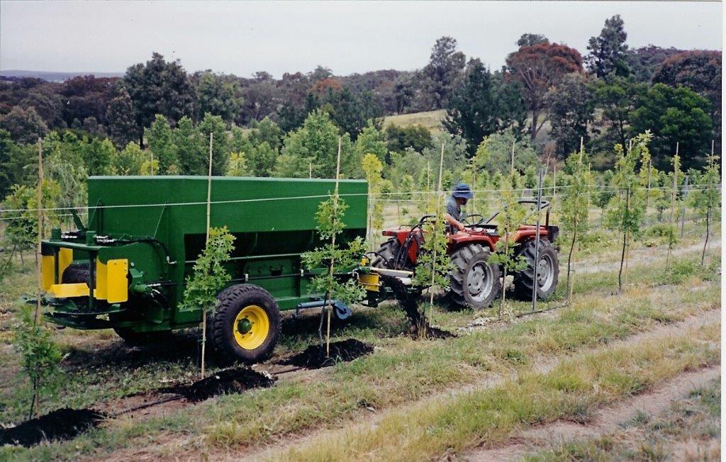 A photo of a farmer applying biosolids on an orchard.