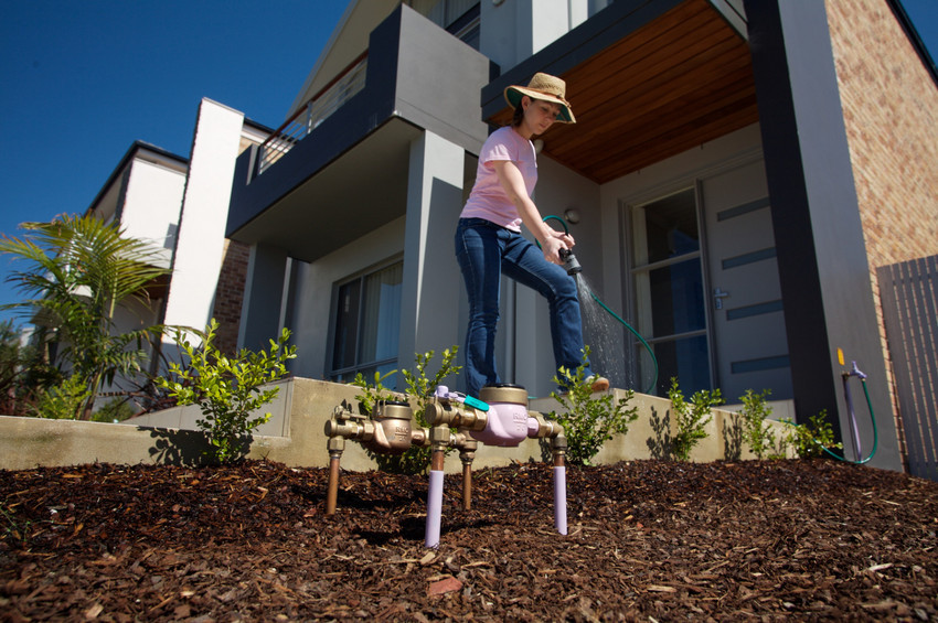 A woman waters her garden with recycled water.