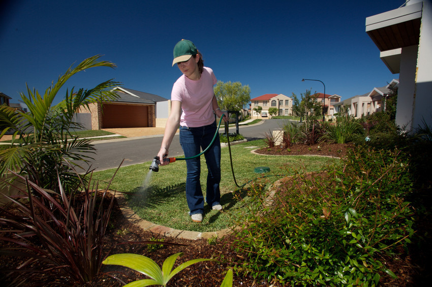 A woman waters her garden with recycled water.
