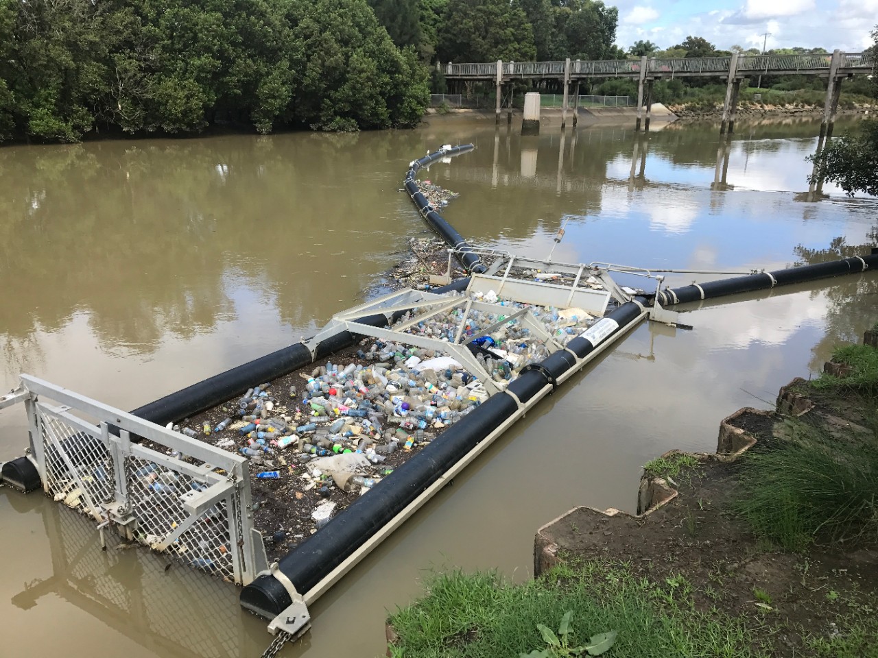 A photo of a stormwater quality improvement device collecting rubbish from a waterway.