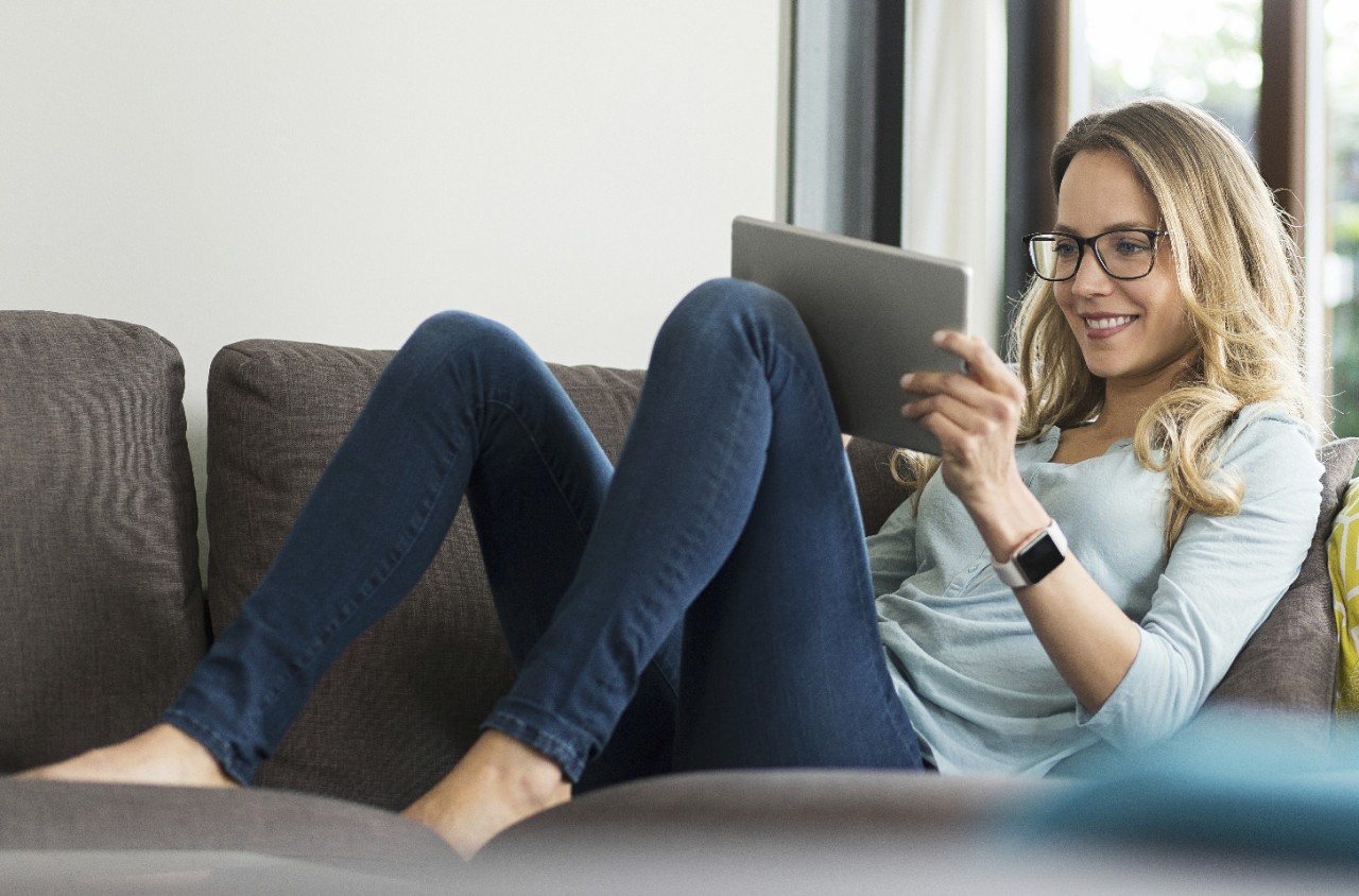 Woman on couch looking at a tablet.