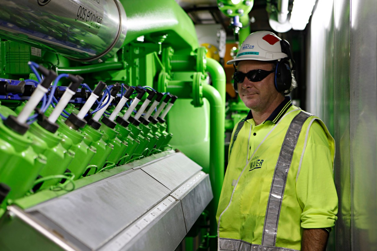 A plant operator next to a cogeneration engine, which is used to produce energy. 