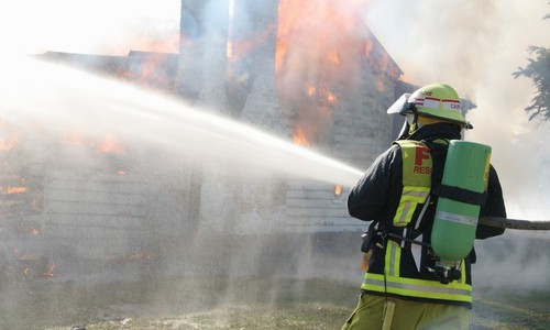 Firefighter hosing a fire.