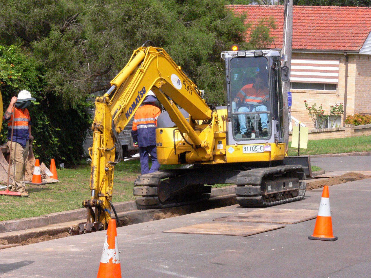 Machinery digging trench in a street.