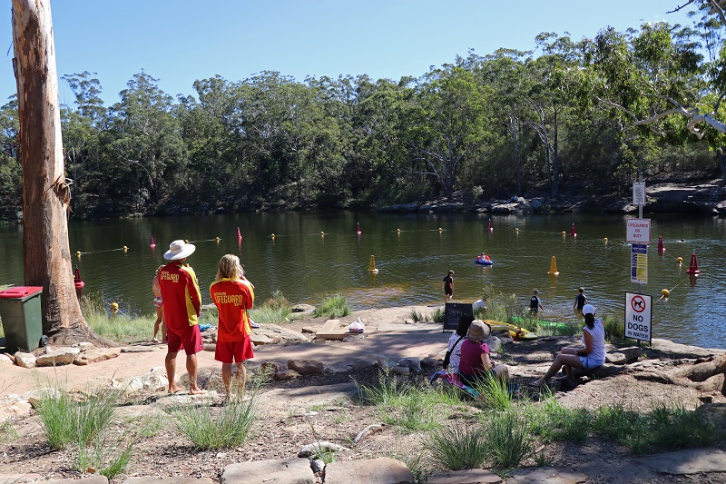 Families having fun in Lake Parramatta, with life guards watching on.