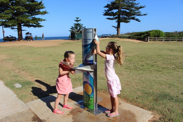 Two girls filling up their drink bottles from our water stations