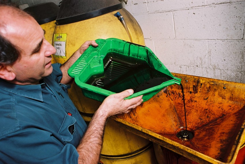 Man collecting used engine oil to dispose of it correctly. 